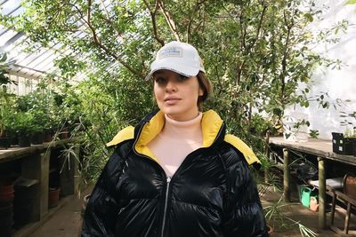 Portrait of young woman standing against trees