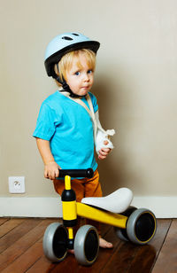 Portrait of boy playing with toy while standing against wall