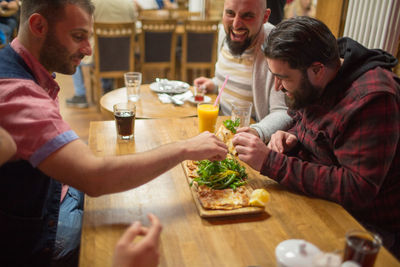 Happy mid adult friends having food in restaurant