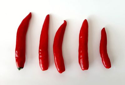 High angle view of red chili peppers over white background