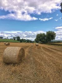 Hay bales on field against sky