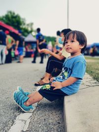 Side view of boy sitting on street