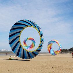 Multi colored balloons on beach against sky