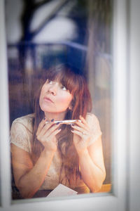 Young woman sitting on window