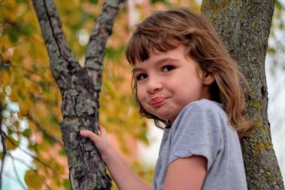 Close-up of smiling girl on tree trunk