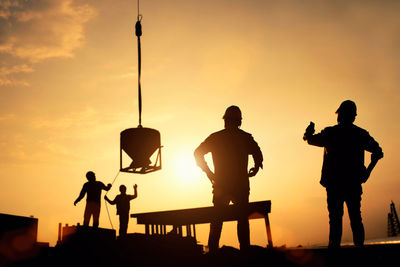 Low angle view of silhouette people working at construction site during sunset