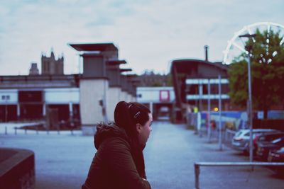 Side view of thoughtful young woman looking away while standing on street