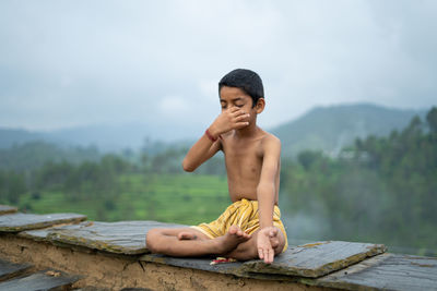 A young indian cute kid doing yoga in the mountains,wearing a dhoti, anulom vilom