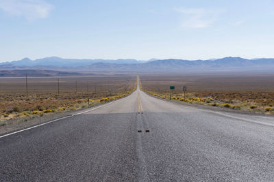 Road leading towards mountains against sky