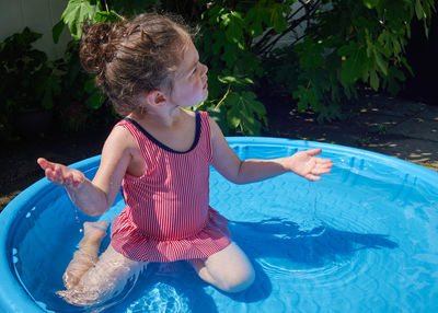 Cute toddler playing in the water basin in the backyard