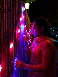 Side view of man standing against illuminated lights