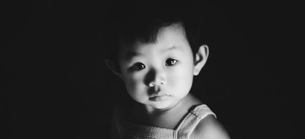 Portrait of cute boy against black background