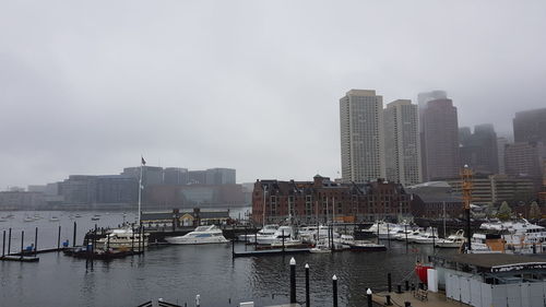 Boats moored in harbor against buildings in city