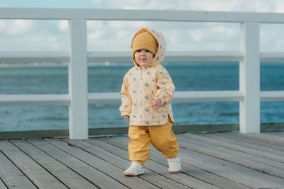 Full length of boy standing on pier at beach