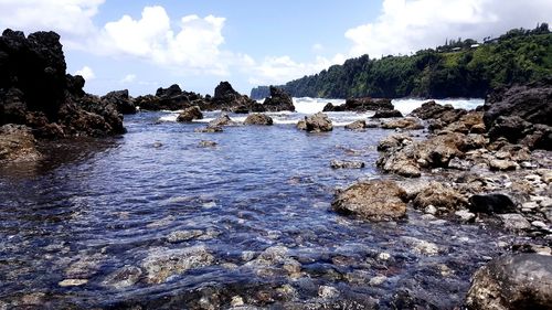 Scenic view of rocks in sea against sky