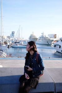 Young woman looking at harbor against sky