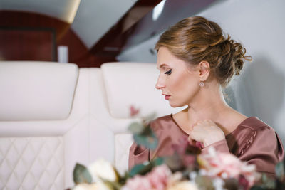 Beautiful woman in private jet in stylish dress with hairstyle and make-up sits