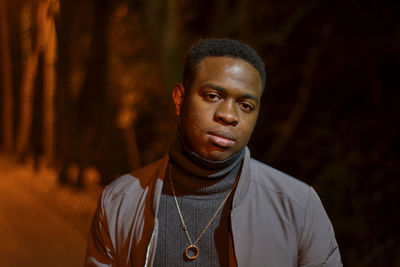 Portrait of serious young man standing outdoors at night