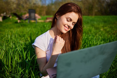 Portrait of young woman using laptop at park