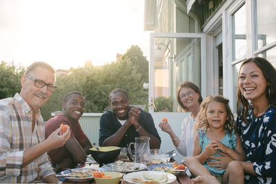 Portrait of smiling multi-generation family enjoying lunch at table on porch