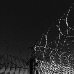 Low angle view of barbed wire fence against sky