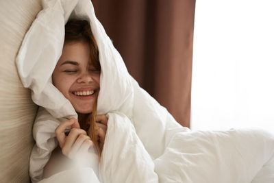 Portrait of smiling young woman relaxing on bed at home