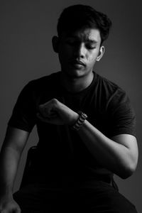 Portrait of young man standing against black background