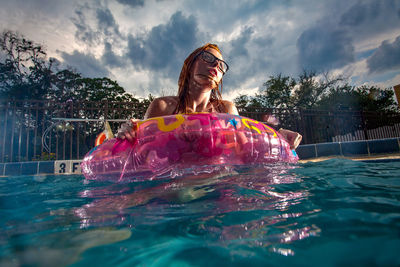 Woman enjoying in swimming pool against sky