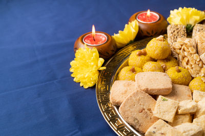 Indian traditional sweets laddu, soan papdi, burfi for festival on blue background with copy space