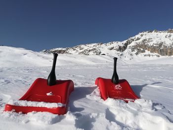 Red umbrella on snow covered mountain against sky