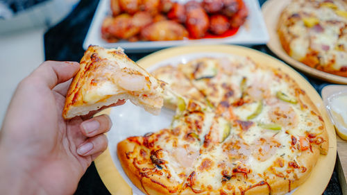 Close-up of hand holding pizza