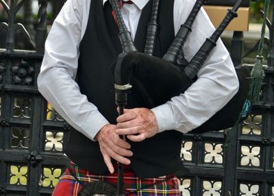 Midsection of man holding umbrella while standing outdoors