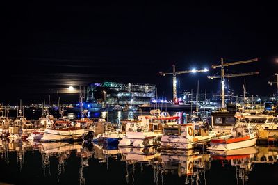 Boats moored in harbor at night