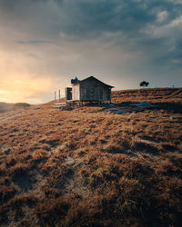 House on field against sky during sunset
