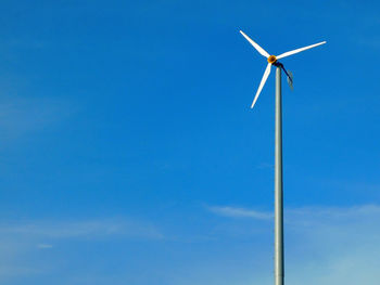 Low angle view of windmill against blue sky