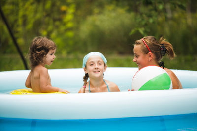 Mother with daughters relaxing in wading pool