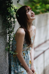 Portrait of young woman standing against plants