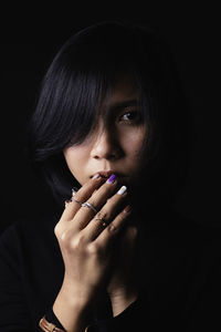 Close-up portrait of young woman against black background