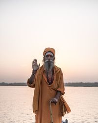 Man by sea against clear sky during sunset