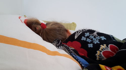 Close-up of girl lying down on bed at home