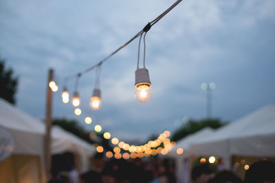 Low angle view of illuminated light bulb against sky at dusk