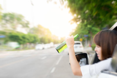 Woman holding umbrella on road in city