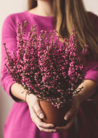 Close-up of young woman offering potted purple flowers