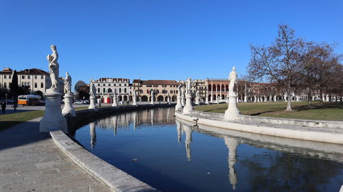 Statue by pond against blue sky