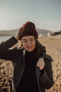 Aesthetic portrait of young girl in a multi-layered style of clothing, in maroon hat, gray coat