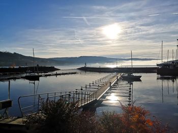 Boats moored in harbor at sunset