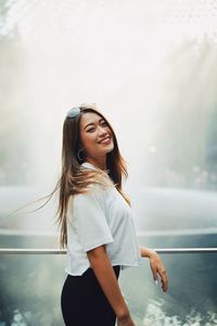 Portrait of smiling woman standing by railing