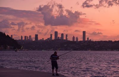 Full length of man standing by sea against sky during sunset