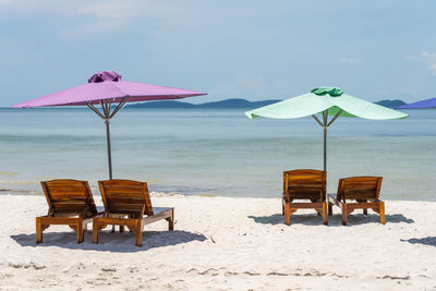 Deck chairs on beach against sky