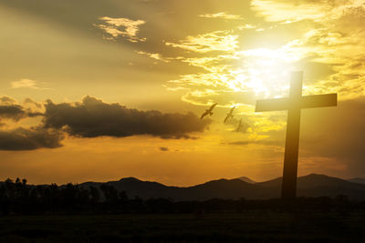 Silhouette cross against sky during sunset